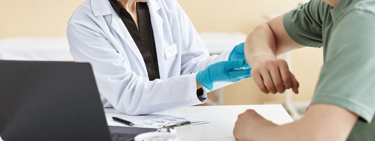 Portrait of mature female doctor inspecting patient with skin rash during consultation in dermatology clinic