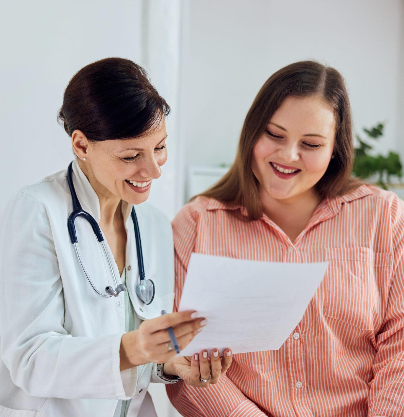 A happy overweight woman is satisfied with her weight loss program results and sitting with a female nutritionist.